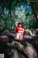 A woman in a red riding hoodie sitting on a rock.