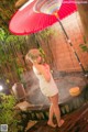 A woman in a white dress standing under an umbrella.