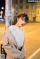 A woman leaning against a pole on a city street.