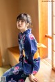 A woman in a blue kimono sitting on a window sill.