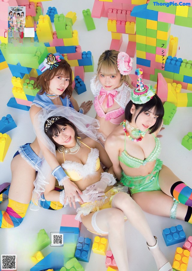 A group of young women sitting on top of a pile of lego blocks.